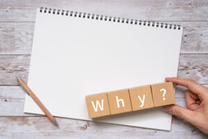 「Why?」と書かれた積み木とノート、ペン