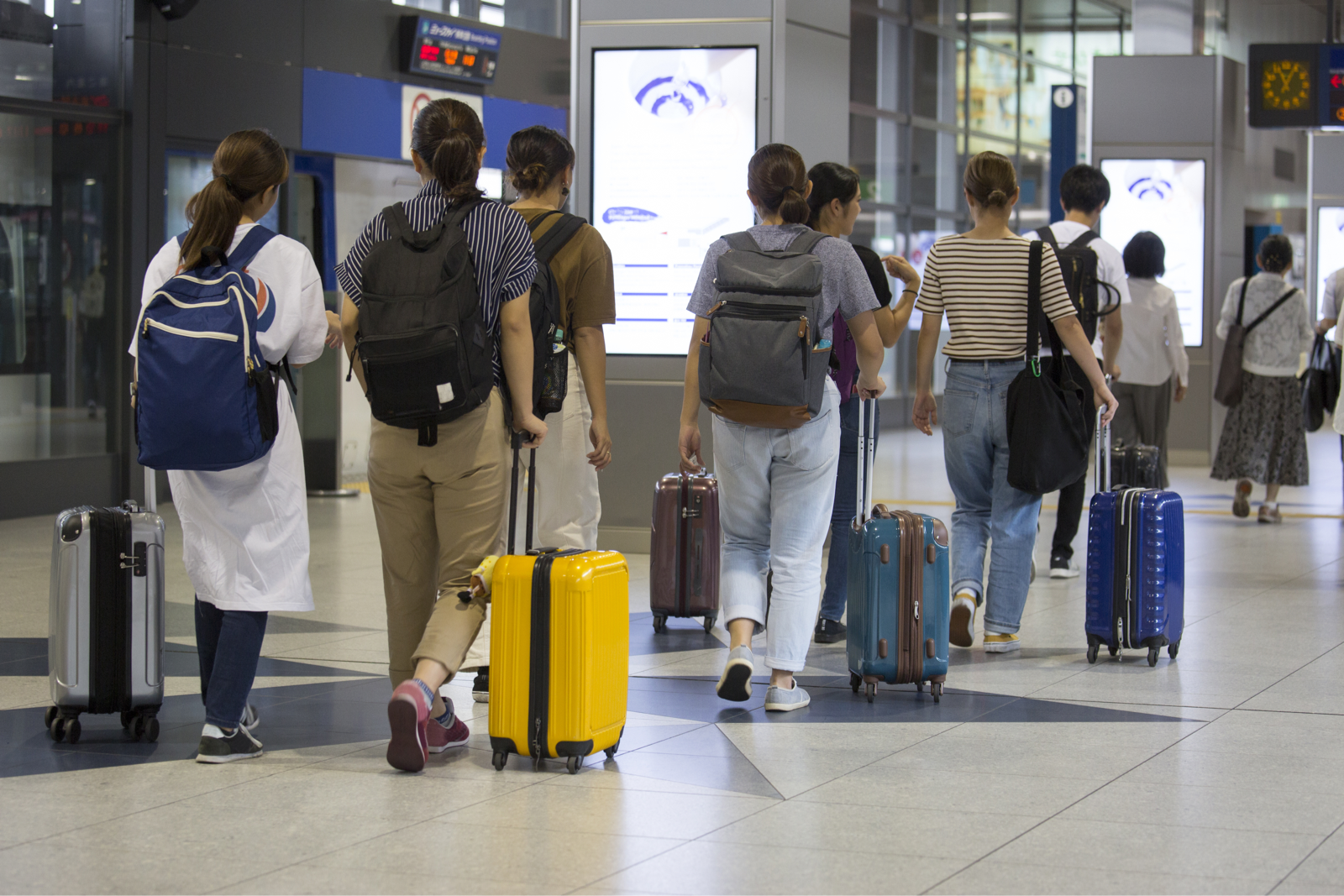 空港でスーツケースを引く外国人旅行客