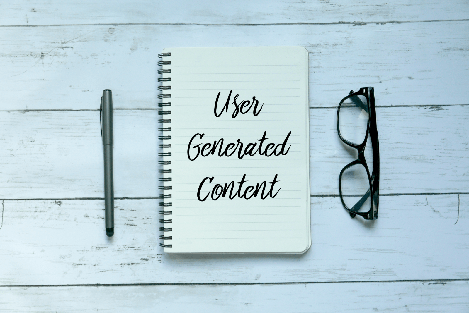 User Generated Contentと書かれたノート、ペン、メガネ