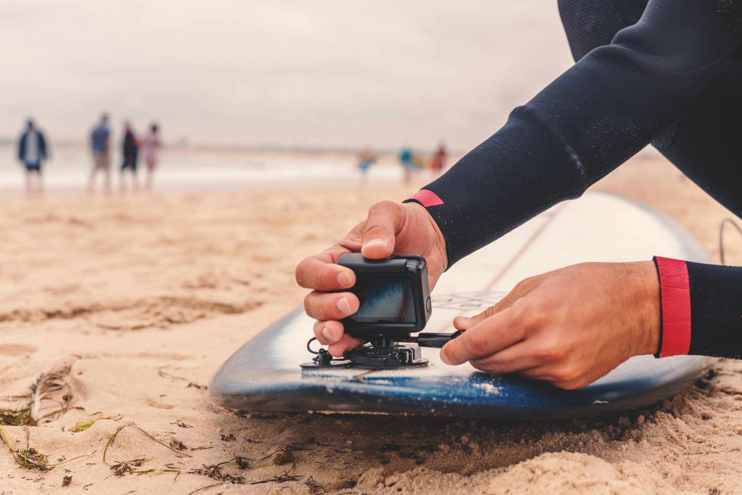 砂浜でサーフボードに人間がカメラを取り付けている