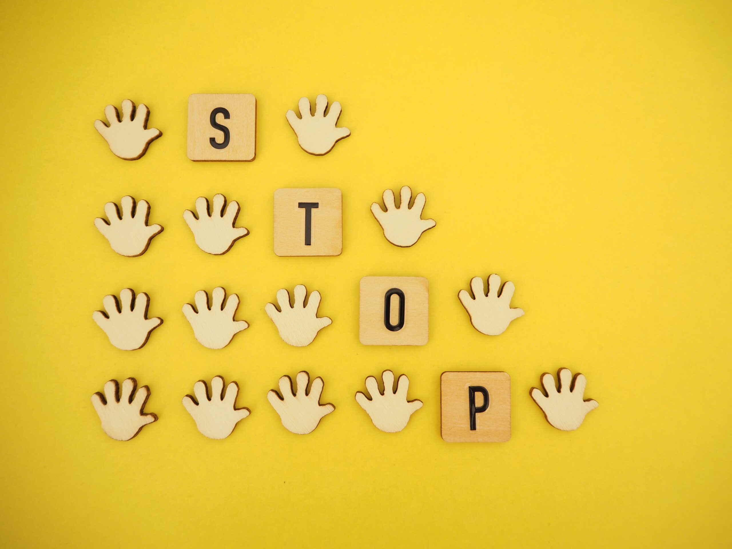 黄色い背景に複数の手とSTOPの文字